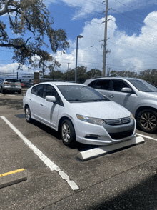 a white honda car is parked on a curb in a parking lot