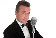 a man in a tuxedo is holding a microphone and making a funny face