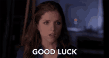 a woman says " good luck " in front of a dark background