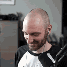 a bald man with a beard wearing ear buds and smiling