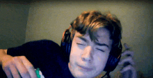 a young man wearing headphones is making a funny face with his eyes closed