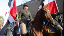 a woman in a military uniform is riding a horse while holding a flag