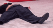 a man in a suit is laying on his back on the floor .