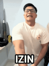 a man wearing glasses and a white shirt has the word izin on his shirt