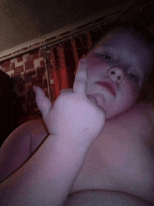 a shirtless child giving a thumbs up in a dark room