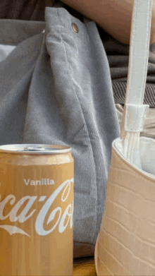 a can of vanilla coca cola is next to a purse