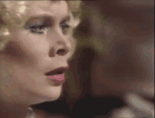 a close up of a woman 's face with her mouth open and a man in the background .