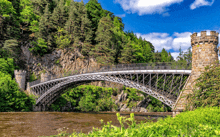 a bridge over a river surrounded by trees on a sunny day