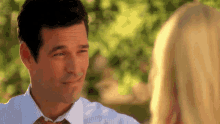 a man in a white shirt and tie looks at a blonde woman