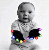 a baby is wearing a pair of black gloves with colorful lights on them