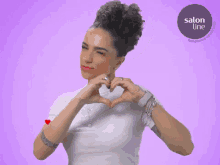 a woman making a heart shape with her hands with a salon line logo in the corner