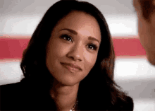 a woman is smiling while looking at a man in front of a red and white striped wall .