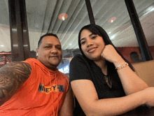 a man wearing an orange nike shirt sits next to a woman wearing a black shirt