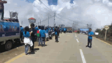 a group of people are standing on the side of a road in front of a sign that says ' atencion '