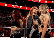 three women are standing in a wrestling ring with a sign that says raw in the background