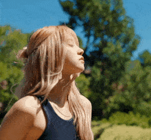 a woman with her eyes closed stands in the sun