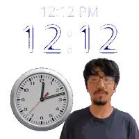 a man with glasses stands next to a clock that says 12:12