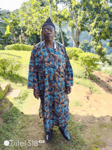 a man is standing in a field with a ditel s18 4g phone behind him