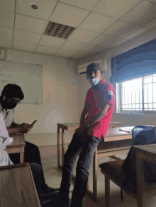 a man in a red shirt is standing in a classroom with a white board that says physics on it