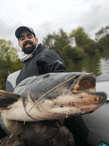 a man in a boat holding a large catfish