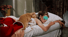 a woman wearing a sleep mask is laying in bed with her cat
