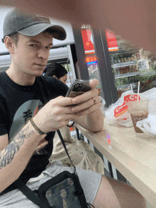 a man with a tattoo on his arm is looking at his cell phone