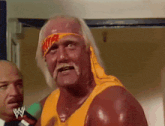 hulk hogan is wearing a yellow shirt and a headband with a wwe logo on it