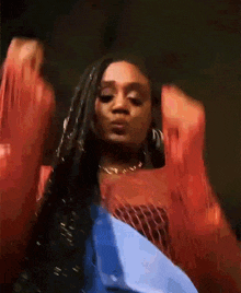 a woman in a red top is dancing with her arms outstretched .