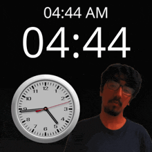 a man with glasses stands in front of a clock that reads 4:44 am