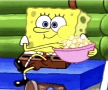 spongebob squarepants is sitting on a box eating popcorn from a pink bowl .