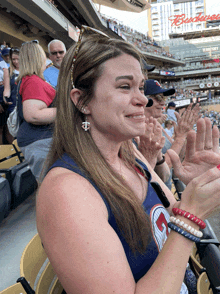 a woman sitting in a stadium with a budweiser sign