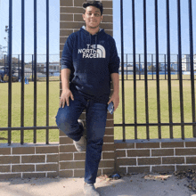 a man leaning against a brick wall wearing a hoodie that says the north face