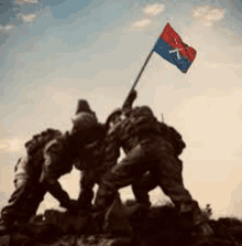 a group of soldiers holding a flag on top of a hill .