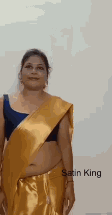 a woman is wearing a yellow satin saree with a blue bra .