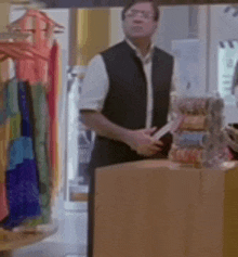 a man in a black vest is standing in a store holding a knife .