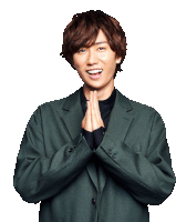 a young man in a green jacket is smiling with his hands together