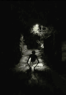 a silhouette of a person walking down a dark alleyway