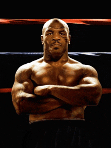 a boxer with his arms crossed stands in a boxing ring