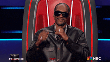 snoop dogg is sitting in a chair with a nbc logo on the bottom right