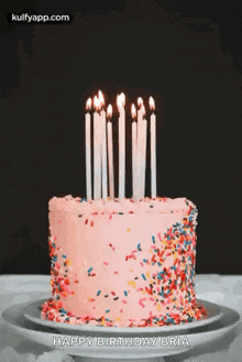 a birthday cake with candles and sprinkles is on a plate .