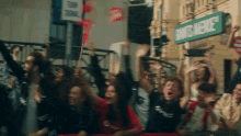 a group of people are raising their hands in the air in front of a sign that says saints avenue