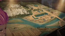 a woman looks at a model of a city with a river and buildings