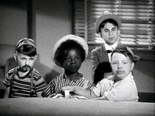 a group of young boys are sitting around a table in a room .