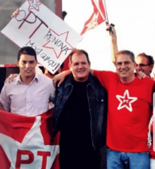 a man in a red shirt with a star on it holds up a sign that says pt renova