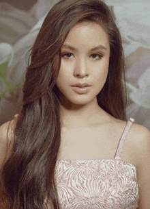 a woman with long brown hair is wearing a pink dress