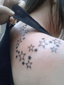 a close up of a woman 's back with a tattoo of stars on it .