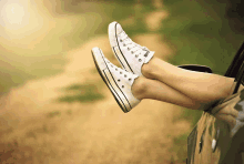 a person 's feet sticking out of a car window wearing white converse sneakers