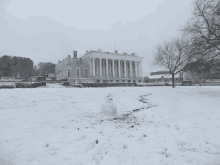 a snowman in front of a large building in the snow