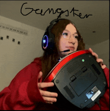 a girl wearing headphones and glasses is holding a computer and the word gangster is written in black marker