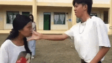 a man is slapping a woman in the face while a woman looks on .